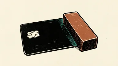 American Express price target lowered by JP Morgan: a blank credit card with an electronic chip is weighted down at one end by a heavy rectangular block.
